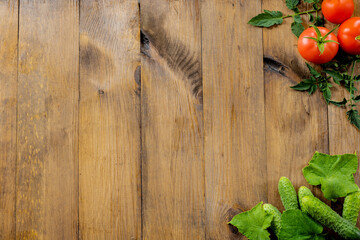 Wooden background. Fresh cucumbers, red tomatoes with leaves on a wooden background. Place for text. copy space.