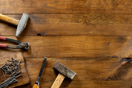 Different carpentry tools on a wooden background. Nail puller, chisel, two hammers, nails on a wooden board. Copy space.