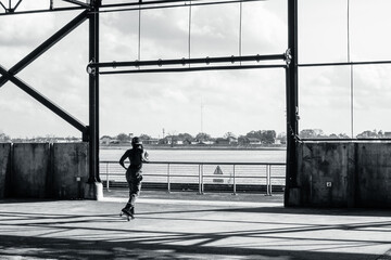 Fototapeta na wymiar Black and White Photo of a Roller Skater in Silhouette in Crescent Park with a View of the Mississippi River and the West Bank on January 9, 2022 in New Orleans, Louisiana, USA