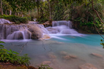 Magical turquoise blue colours of Kuang Si waterfalls Luang Prabang Laos. these waterfalls in the Mountains of Luang Prabang Laos flow all year round in the natural national park rainforest 