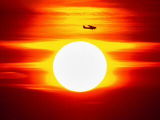 The plane flies into the bloody sunset.