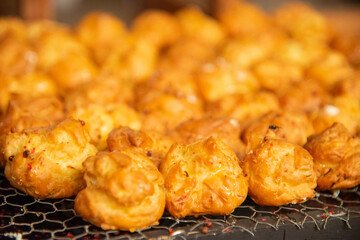 Closeup of bite-sized cheese puffs warmly lit with a shallow depth of field of the multiple pieces on a cooling wire