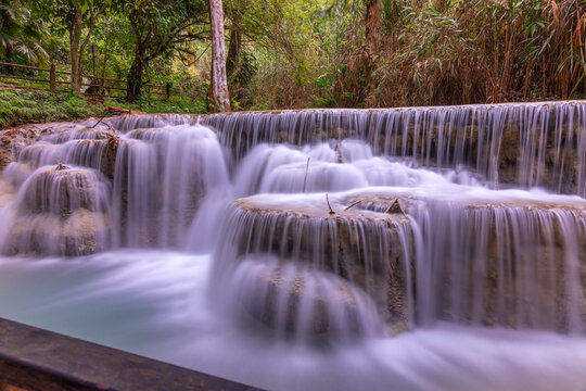 Magical turquoise blue colours of Kuang Si waterfalls Luang Prabang Laos. these waterfalls in the Mountains of Luang Prabang Laos flow all year round in the natural national park rainforest © Elias