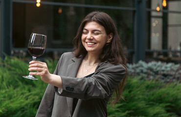A young woman with a glass of wine outside near a restaurant.