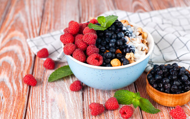 Oatmeal with fresh berries and yoghurt on a wooden table. Healthy breakfast. Сlose-up.