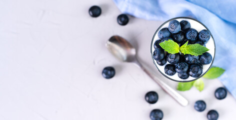 Healthy dessert with fresh blueberries and yogurt in a glass on the grey background. Healthy food....