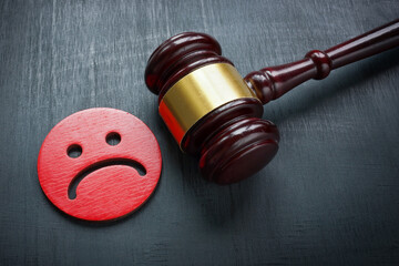 Unhappy smiley and gavel. Discrimination and Bullying law concept.