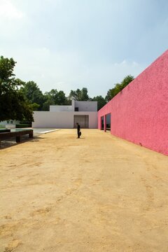 An architectural work of Luis Barragan with smooth pink and white walls beside a pool under open sky