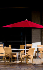 Red Umbrella with Table and Wicker Chairs.