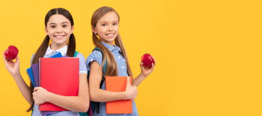 School girls friends. Happy pupils with books hold vitamin organic apples yellow background, school breakfast. Banner of school girl student. Schoolgirl pupil portrait with copy space.