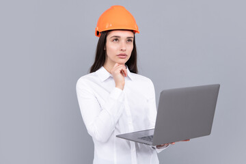 Young woman in hard hat helmet with laptop computer isolated on grey background. Architect woman wear helmet and shirt. Business woman, construction manager, builder.