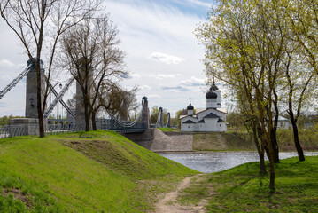 Fototapeta na wymiar Chain Bridge and the Church of St. Nicholas the Wonderworker in the city of Ostrov, Pskov region, Russia