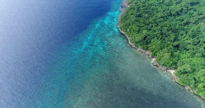Aerial shot of a zodiac floating over shallow colorful coral reef