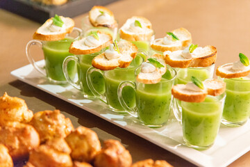 Cocktail soups in small glasses with handles, topped with a slice of bread, dairy and mint garnish