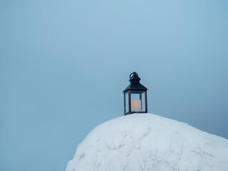 An old candle lantern stands on the evening snow in frosty winter.