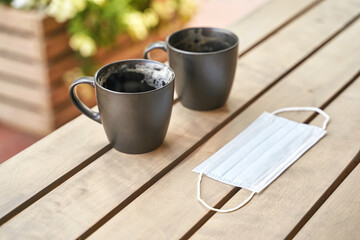 Two drinking coffee in outdoor cafe after drink. Messy cup after breakfast. Protective mask. latte in mug. Lunch casual atmosphere. Lifestyle cozy morning. No people