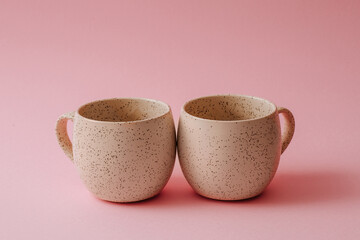 Two porcelain empty cups on a pink background, copy space.