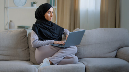 Focused ethnic female muslim arabian young woman girl islamic student businesswoman freelancer sits...
