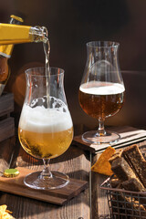 Glasses with beer on a wooden table. Beer is poured into a glass from a bottle. Organic products for home production
