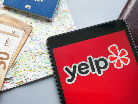 KYIV, UKRAINE - July 21, 2022. Yelp Inc Logo Near A Map And Money.