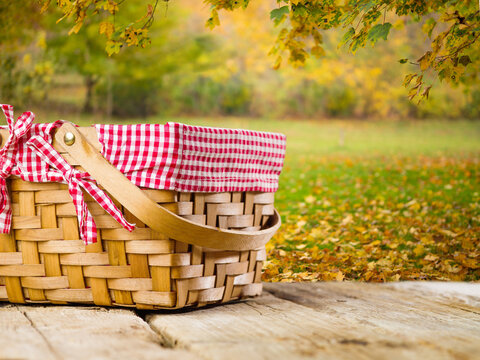 Against the background of golden autumn leaves, a wooden table with a picnic basket. Harvest day celebration, thanksgiving day, family traditions, delicious healthy food.