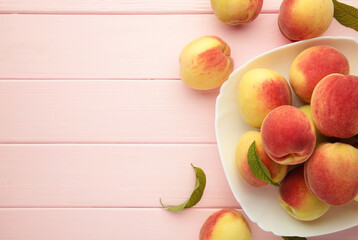 Plate of ripe peaches on pink background. Space for text
