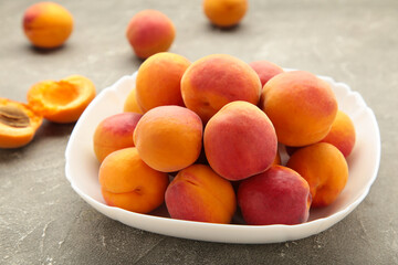 Fresh apricots in the bowl on grey concrete background
