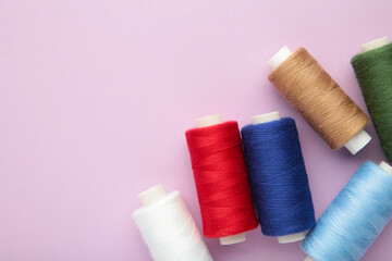 Fototapeta na wymiar Color sewing threads on purple background