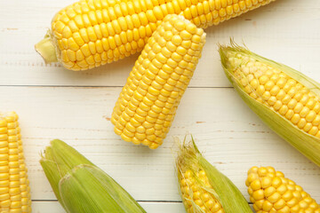 Fresh corn on cobs on white wooden background.