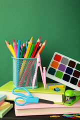 Fototapeta premium School accessories with books on green background. Back to school concept. Vertical photo