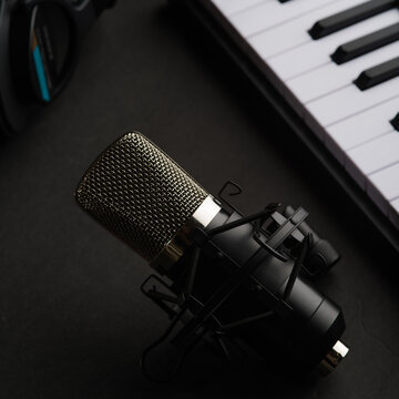 Studio microphone, studio headphones and midi keyboard on a gray background. Recording studio, music studio. There are no people in the photo. Advertising, banner, invitation.