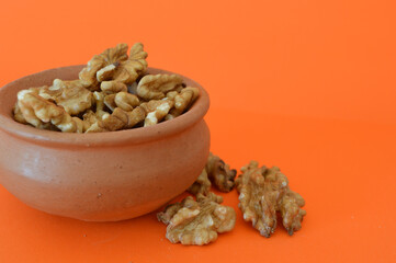 walnuts in ceramic bowl on orange background