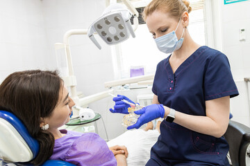 Obraz premium Dentistry concept. Professional dental services and modern equipment without pain. The doctor demonstrates to the patient how to properly brush the teeth