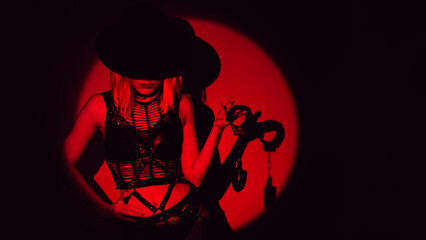 sexy slave girl in underwear and a hat holds handcuffs in hands. Concept of BDSM submissive woman