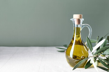 Extra virgin olive oil and olive branch in the bottle on the table with linen tablecloth. Healthy mediterranean food.