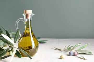 Poster Extra virgin olive oil and olive branch in the bottle on the table with linen tablecloth. Healthy mediterranean food. © Caterina Trimarchi