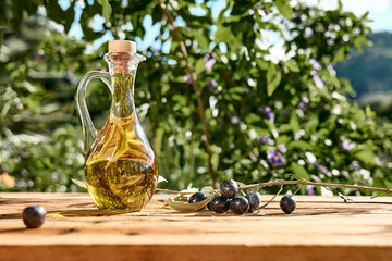 Extra virgin olive oil and olive branch in the bottle on wooden table in the olive grove. Healthy...