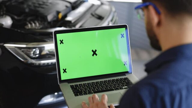 Car service mechanic uses laptop computer with green screen mock up chroma key car diagnostic software. Car Scanner Computer Diagnostics. Automotive Electronic Diagnostic