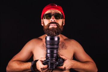 The guy on a black background with a smile. Photographer in a cap with a large camera and lens....
