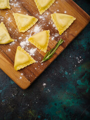 Italian ravioli on a cutting board on a marble background. The process of making homemade ravioli. Home kitchen. Minimalism. Organic food. Healthy lifestyle.