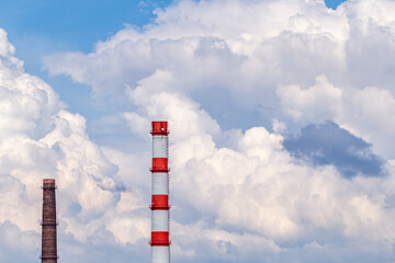 Shot of plant chimneys over blue sky with white puffy fluffy clouds