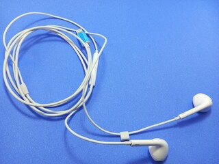 a white earphone with a looped cord on a blue background