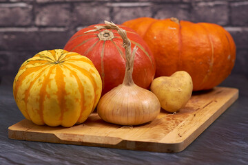 Kürbisgemüse auf Holzbrett vor Ziegelsteinmauer