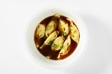 asian steamed dumplings served in chili broth on a white table in a box for delivery
