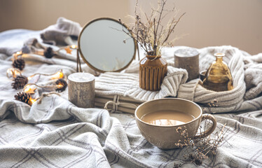 Cozy autumn composition with a cup of coffee and candles in bed.