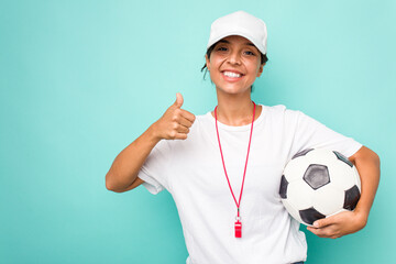 Young hispanic soccer referee woman isolated on blue background smiling and raising thumb up