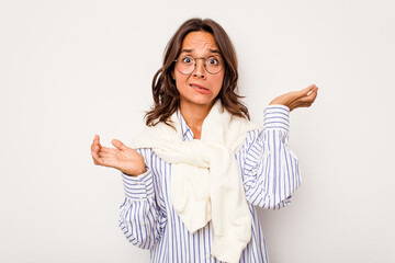 Young hispanic woman isolated on white background confused and doubtful shrugging shoulders to hold...