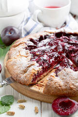 Summer open pie or galette with red plums close up.