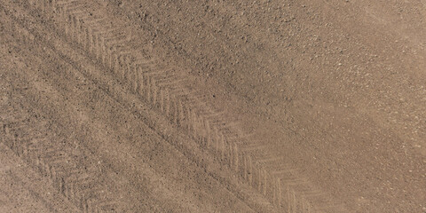 Fototapeta na wymiar panorama of surface from above of gravel road with car tire tracks