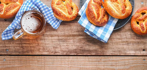 Bavarian pretzels and glass of lager beer. Oktoberfest food menu, traditional salted pretzels over old  wooden background. Top view with space for text. Oktoberfest theme